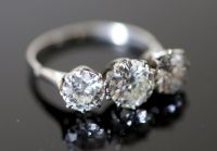 A platinum and three stone diamond ring,                                                                                               