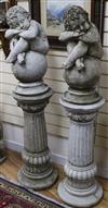 A pair of reconstituted stone columns, surmounted by putti seated on balls H.137cm                                                     