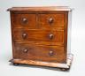 A Victorian stained pine miniature chest of drawers, 27 cms high.                                                                                                                                                           