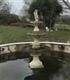 A reconstituted stone three tier garden fountain, surmounted by a putti holding a dolphin                                              