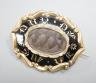 A Victorian yellow metal overlaid and black enamel 'In Memory Of' shaped oval brooch, with central glazed plaited hair panel, 52mm.                                                                                         
