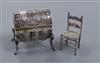 A miniature silver bureau with pseudo-Hanau marks, import marks for Samuel Boyce Landeck and a miniature white metal chair             