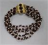 A garnet and seed pearl bracelet with yellow metal clasp.                                                                              