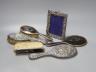 A George V silver and tortoiseshell mounted brush set and a tow similar embossed silver items(a.f.) and a silver mounted photograph frame.                                                                                  