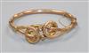 An early 20th century 9ct gold hinged bangle with scrolling motif.                                                                     