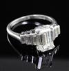 A 1930's/1940's Art Deco platinum and single stone emerald cut diamond ring, with graduated baguette cut diamond set shoulders,        