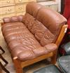 A brown leather two seater Scandinavian sofa                                                                                           