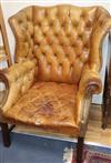 A pair of leather tan wing armchairs                                                                                                   