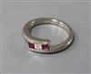 A modern 18ct white gold, three stone ruby and diamond ring, size N.                                                                   