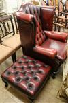 A buttoned red leather wing back armchair and footstool                                                                                