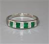 A modern white metal and nine stone emerald and diamond set half eternity ring, size W.                                                