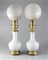 A pair of mid 19th century French ormolu mounted celadon porcelain oil lamps, with opaque circular glass shades, height 23in.          