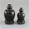 Two Chinese miniature black glazed double gourd vases, 18th century, H. 9.5cm and 7.4cm, tiny rim chip, wood stands                    