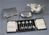 A circular silver tobacco box, a sauce boat, a cigarette box and a cased set of coffee spoons                                          