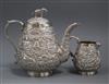 An Indian embossed white meta teapot and matching cream jug.                                                                           