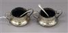 A pair of George V Art Nouveau silver two handled salts and two associated plated spoons.                                              