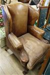 A George II-style mahogany brown leather upholstered wing armchair                                                                     