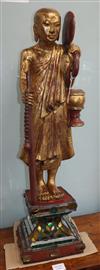 A Tibetan carved giltwood figure of a monk on mirrored plinth base                                                                     