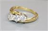 An 18ct gold and three stone diamond crossover ring, size N/O.                                                                         