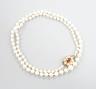 A single strand graduated cultured pearl necklace, with 9ct, garnet and cultured pearl cluster set clasp, 53cm.                                                                                                             