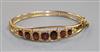 A 9ct gold and garnet set hinged bangle.                                                                                               