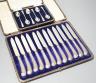A cased set of twelve reeded silver pistol handled steel dessert knives and a cased set of six silver teaspoons.                                                                                                            