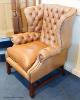 A George III style buttoned tan leather wingback armchair                                                                                                                                                                   