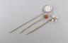 An Edwardian yellow metal, seed pearl and diamond set stick pin, 57mm and two other stick pins.                                                                                                                             