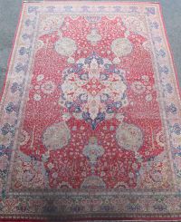 A Kirman carpet, the claret field with overall flowering shrub and palmette design centred by an indigo hooked medallion.              