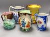 A Burleigh 'Earth laughs' jug, a majolica jug, a Wade heath jug, a Handleys jug and a salt cellar                                                                                                                           