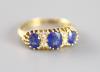 An Edwardian 18ct gold and three stone sapphire set half hoop ring with diamond chip spacers                                                                                                                                