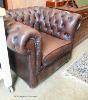 A buttoned brown leather Chesterfield armchair.                                                                                                                                                                             