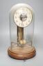 A Bulle electric pendulum clock, with large central brass pillar supporting the 14cm. dial, under a glass dome on a mahogany plinth                                                                                         