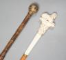 An early 20th century ivory ‘sphinx’ parasol handle, 84cm, together with another gold and iron damascened parasol handle, 62cm                                                                                              