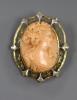 An early 20th century yellow and white metal mounted oval coral pendant brooch, carved with the bust of a lady to sinister                                                                                                  