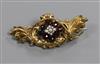 A late Victorian, yellow metal, garnet and pearl scroll brooch, 52mm.                                                                  