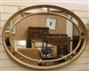 A gilt-framed oval wall mirror with marginal plates W.122cm                                                                            