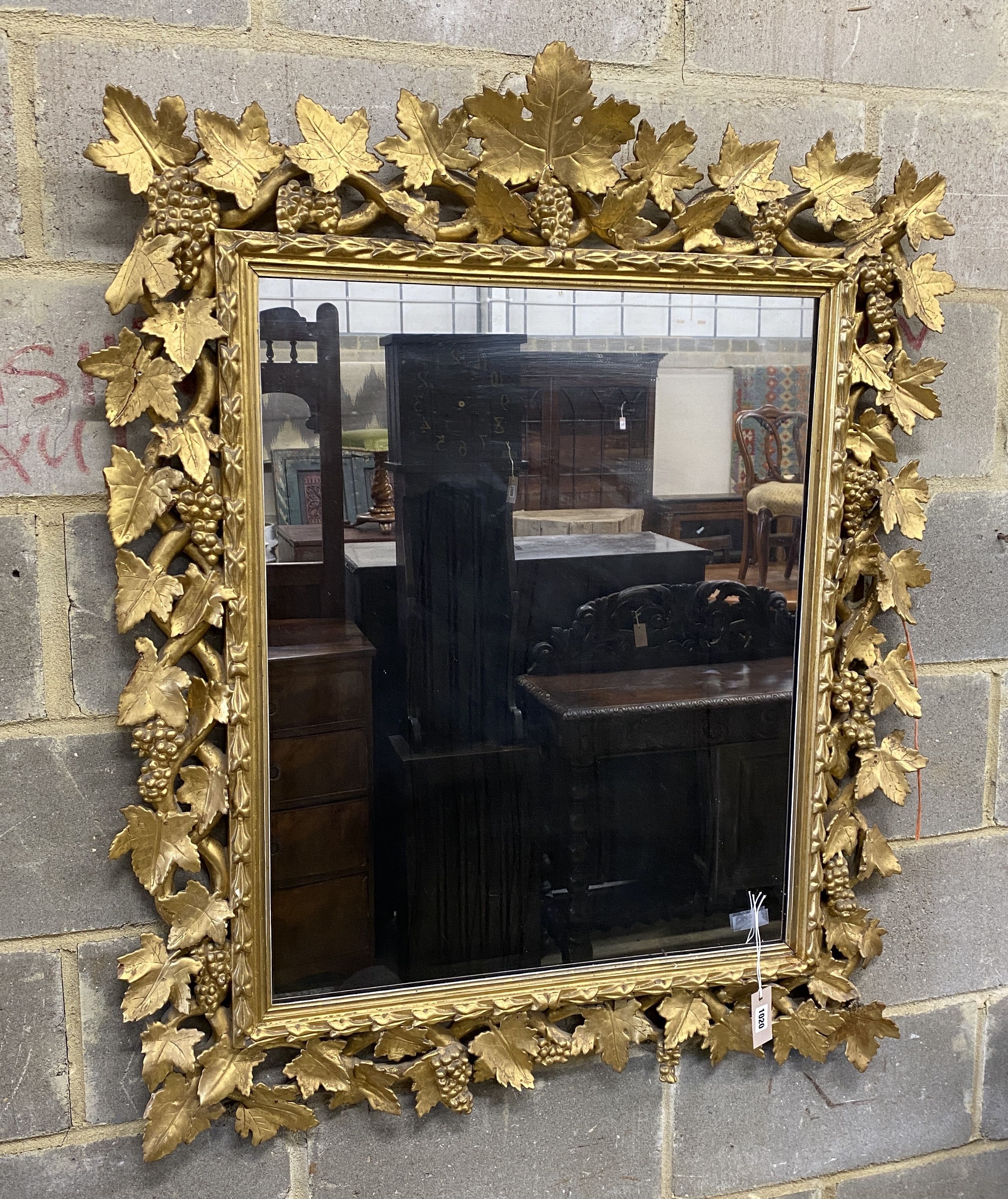 A late 19th century Florentine carved giltwood wall mirror with vineous frame width 97 cm Height 116 cm.
