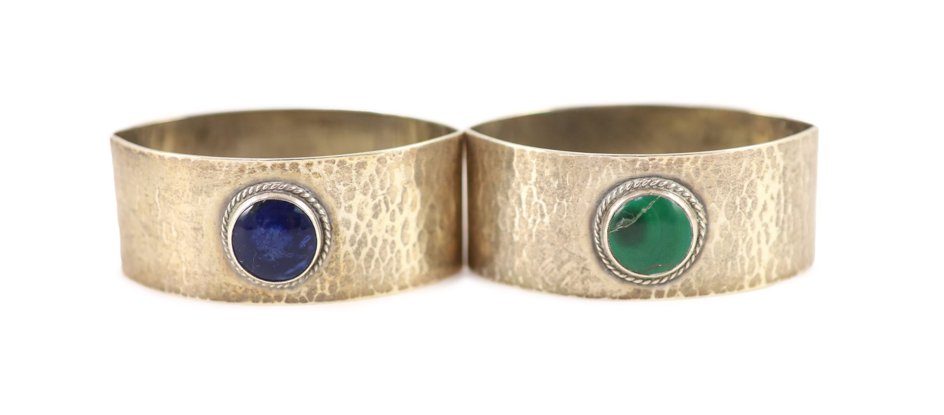 A pair of 1930's Liberty & Co planished silver navette shaped napkin rings, with inset cabochon stone