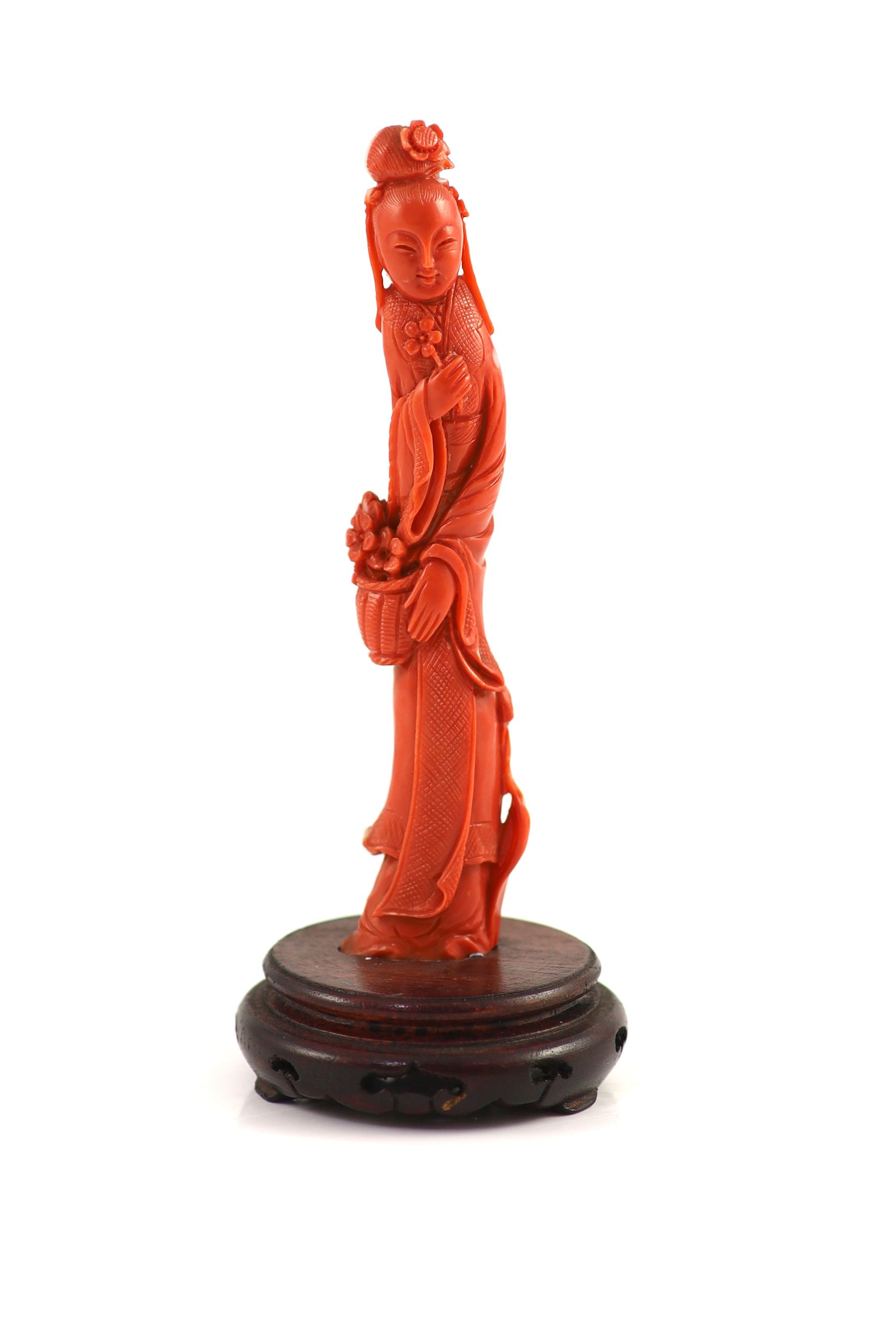 A Chinese coral figure of a tall lady holding a basket of flowers, mid 20th century, 13.4 cm high, 77 g, wood stand