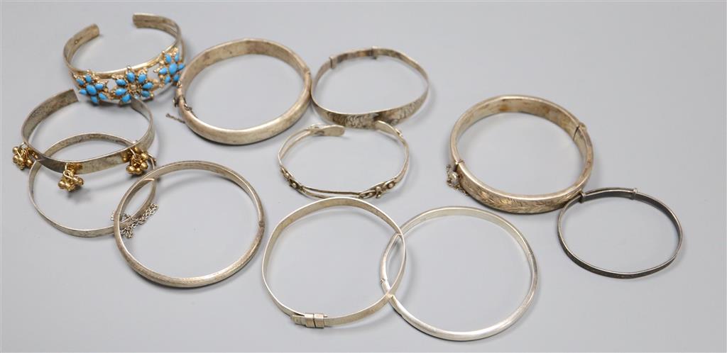 Eleven assorted silver or white metal bangles.