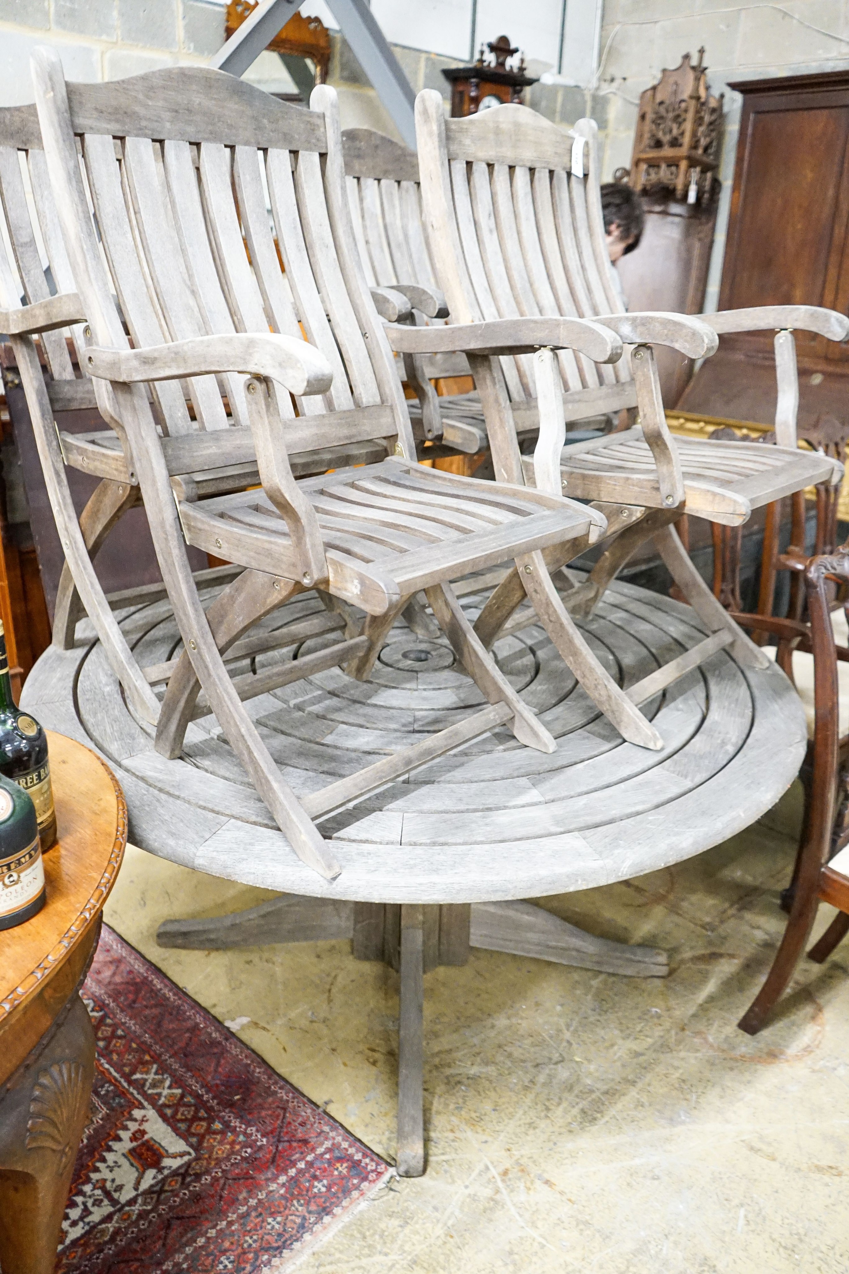An Alexander Rose circular weathered teak garden table, diameter 144cm, height 71cm, (no bolts) and four Kent collection folding chairs