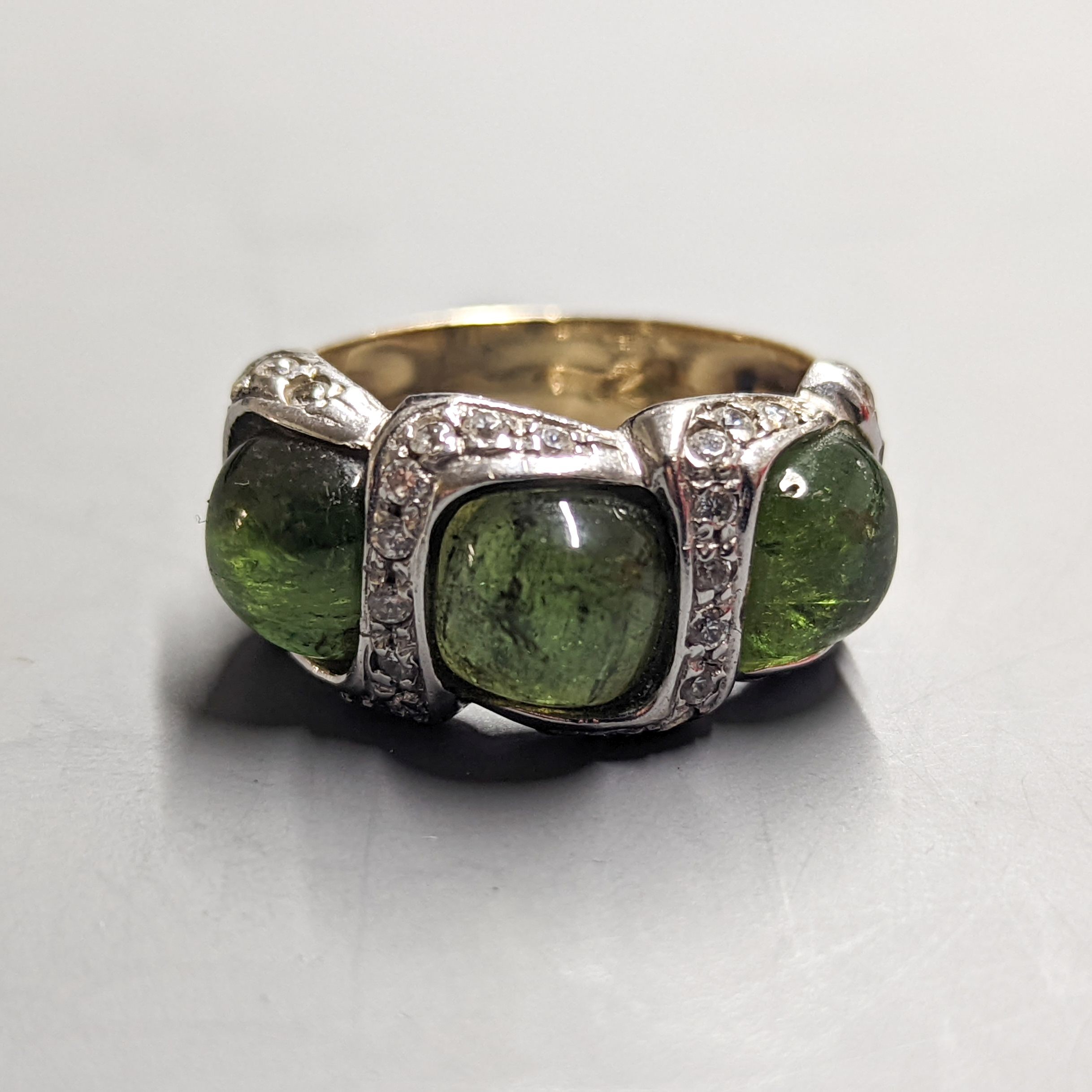 A modern 585 yellow metal, three stone green cabochon and diamond chip set dress ring, size N/O, gross weight 8.3 grams.