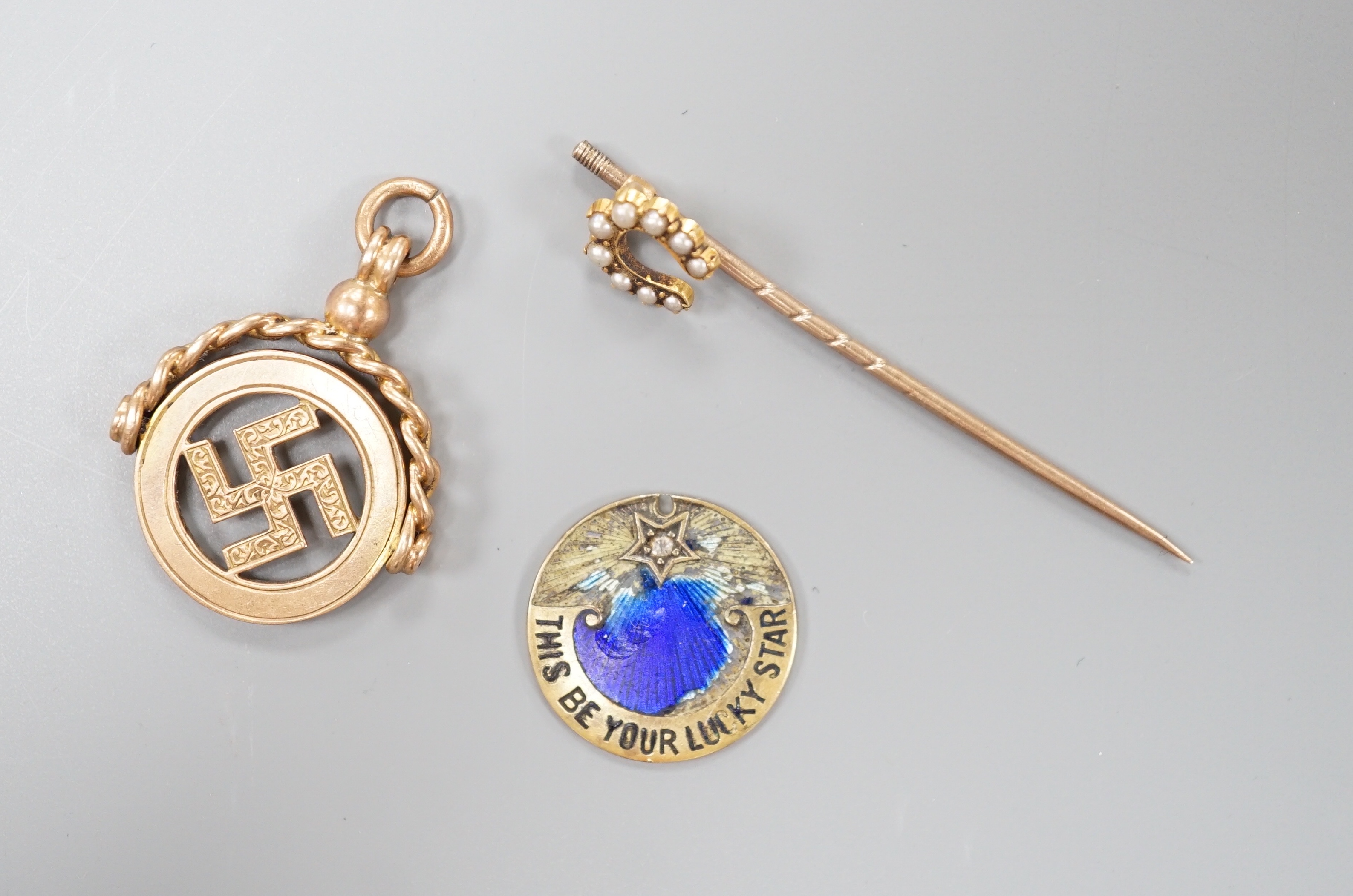 A 1920's pendant, 26mm, a yellow metal and split pearl set horseshoe stick pin and a damaged yellow metal and enamel pendant, gross 7.3 grams.