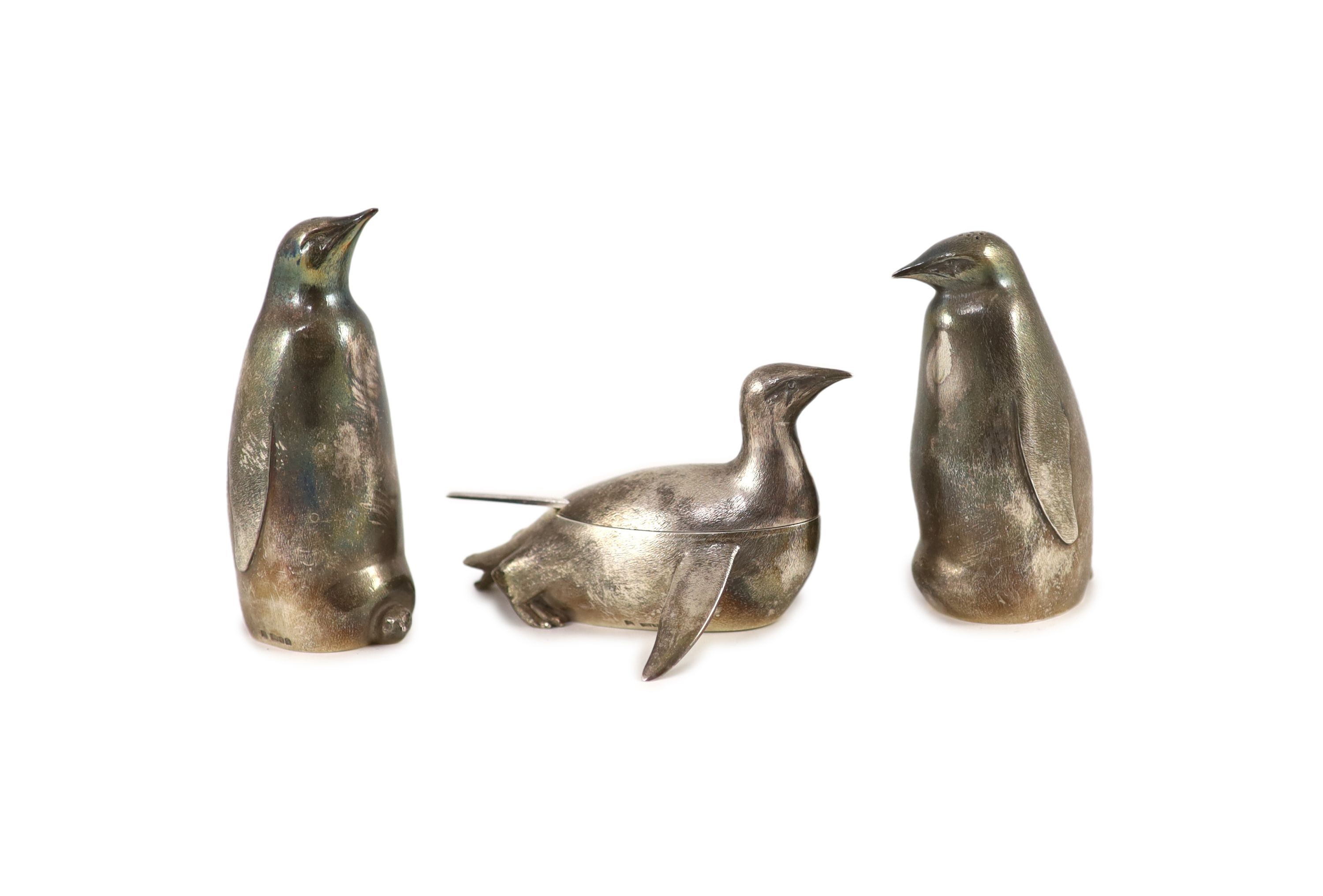 A modern textured silver novelty three piece condiment set, modelled as three penguins, two standing, one laying down
