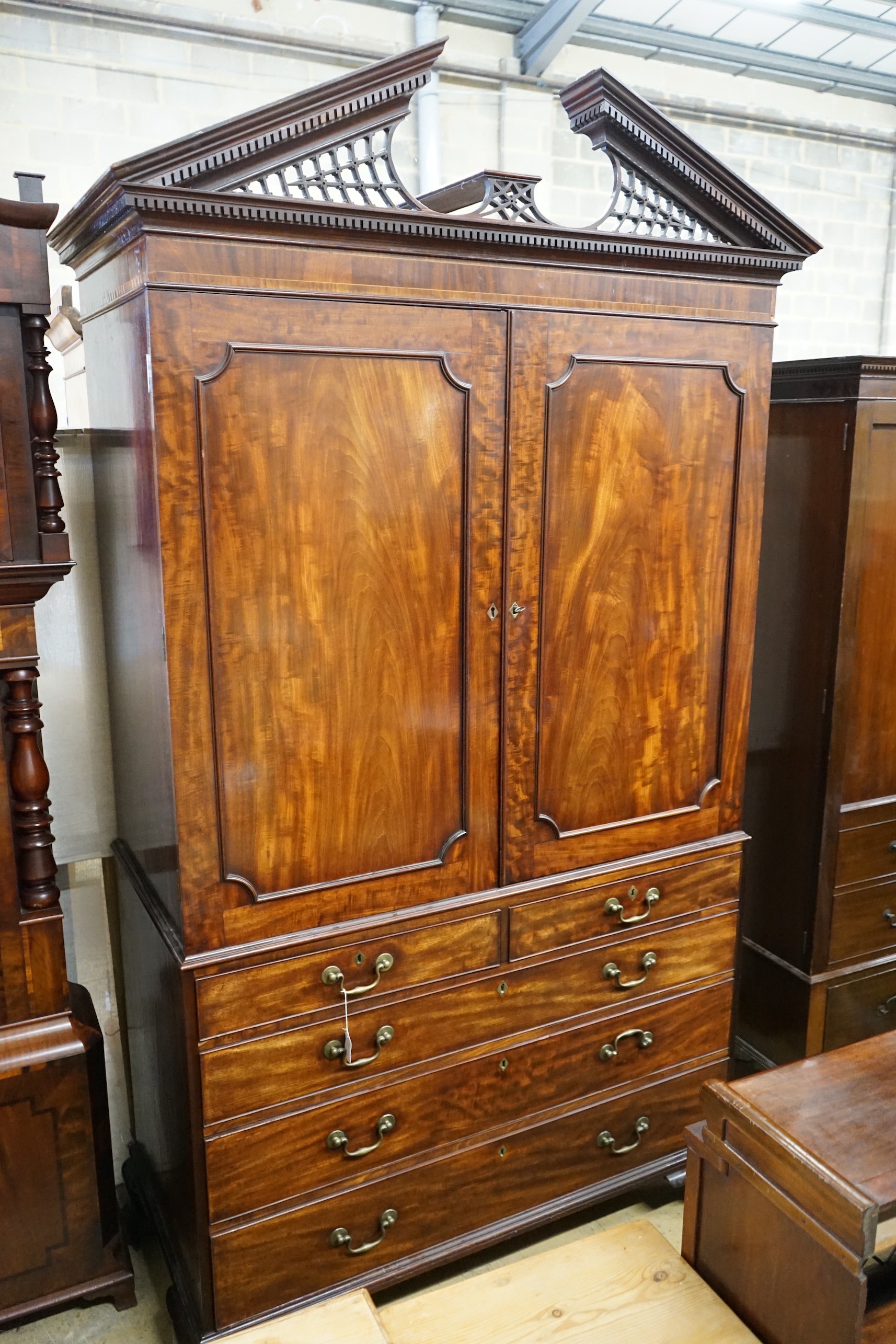 A George III flamed mahogany linen press with broken arch pediment, interior adapted, width 64cm, depth 240cm, height 132cm