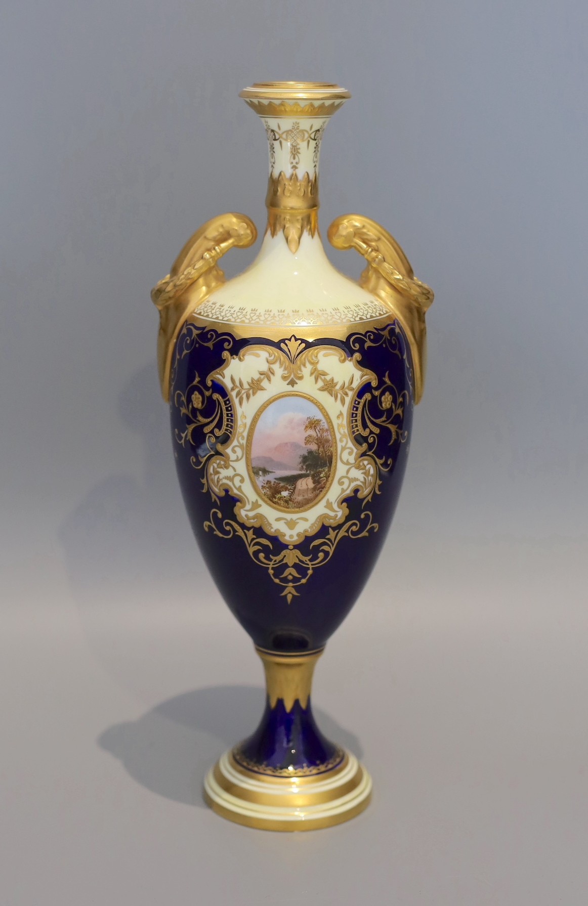 An early 20th century Coalport porcelain vase painted with a view of lake Windermere on a cobalt blue and ivory ground, height 29 cms.