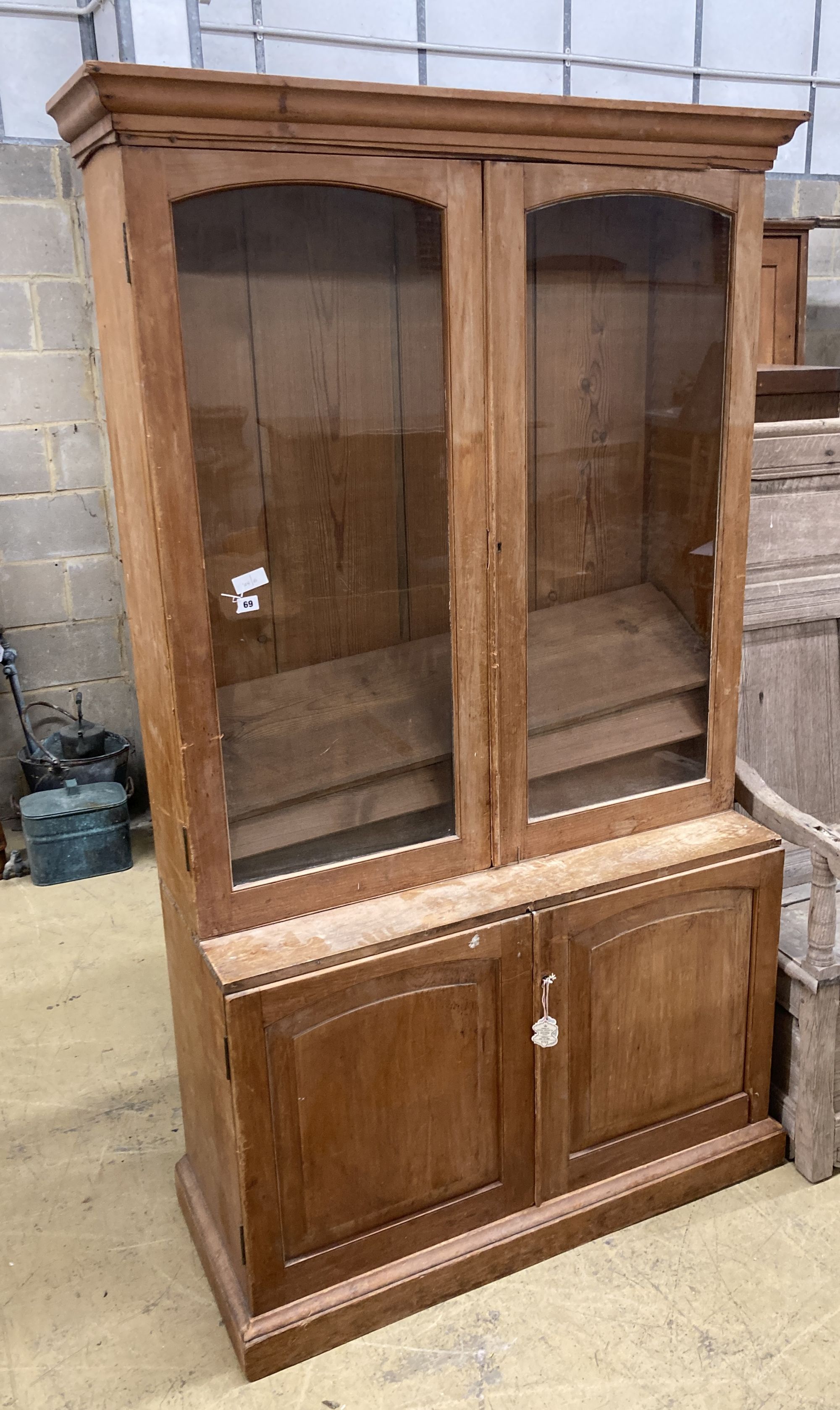 A glazed pine bookcase / cupboard, width 106cm, depth 46cm, height 196cm