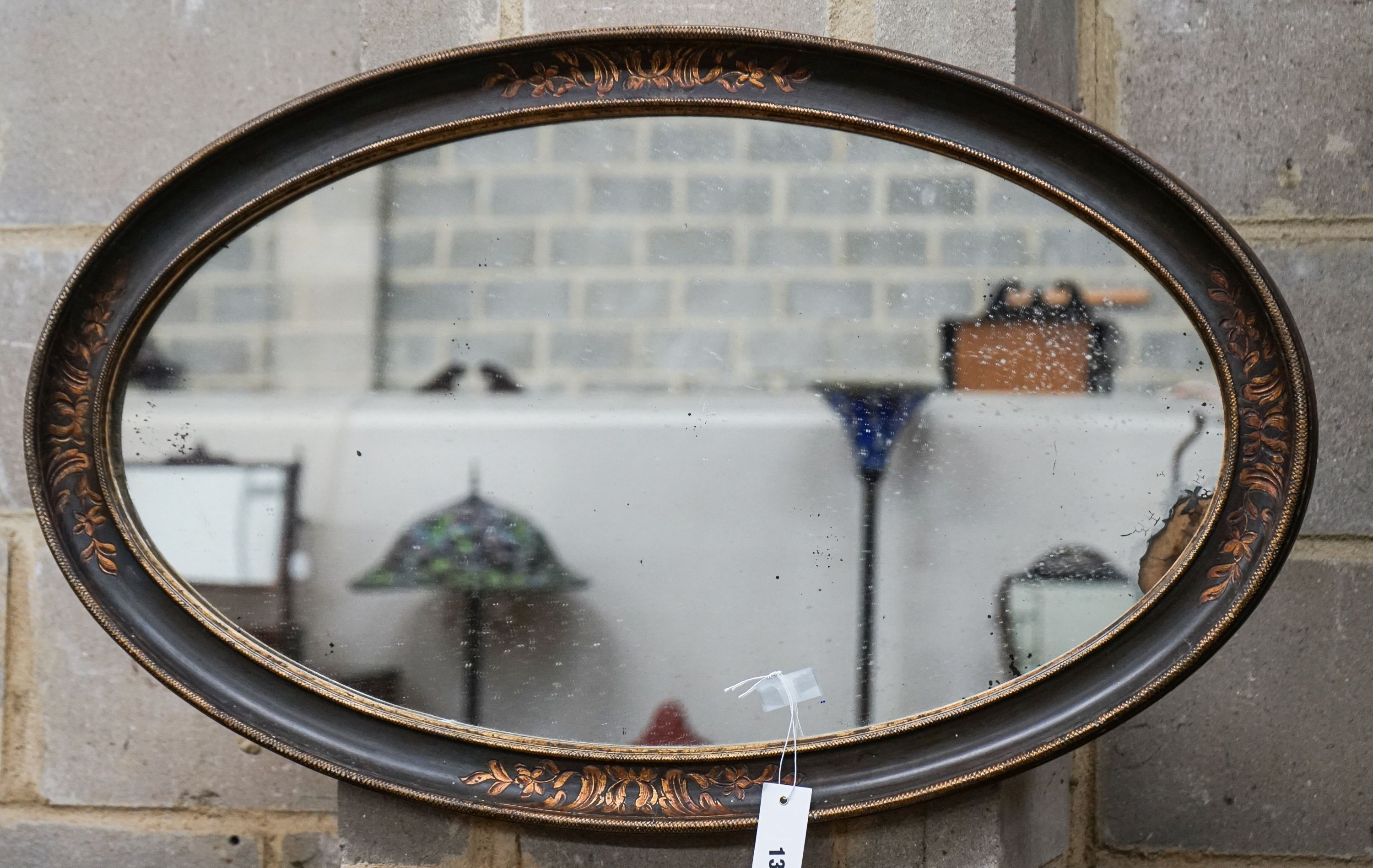 An oval painted parcel gilt bevelled wall mirror, width 84cm, height 51cm