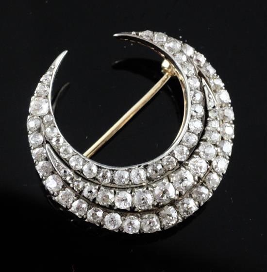 An early 20th century gold and silver, triple row diamond set crescent pendant brooch, 29mm. An early 20th century gold and silver, triple row diamond set crescent pendant brooch, 29mm.